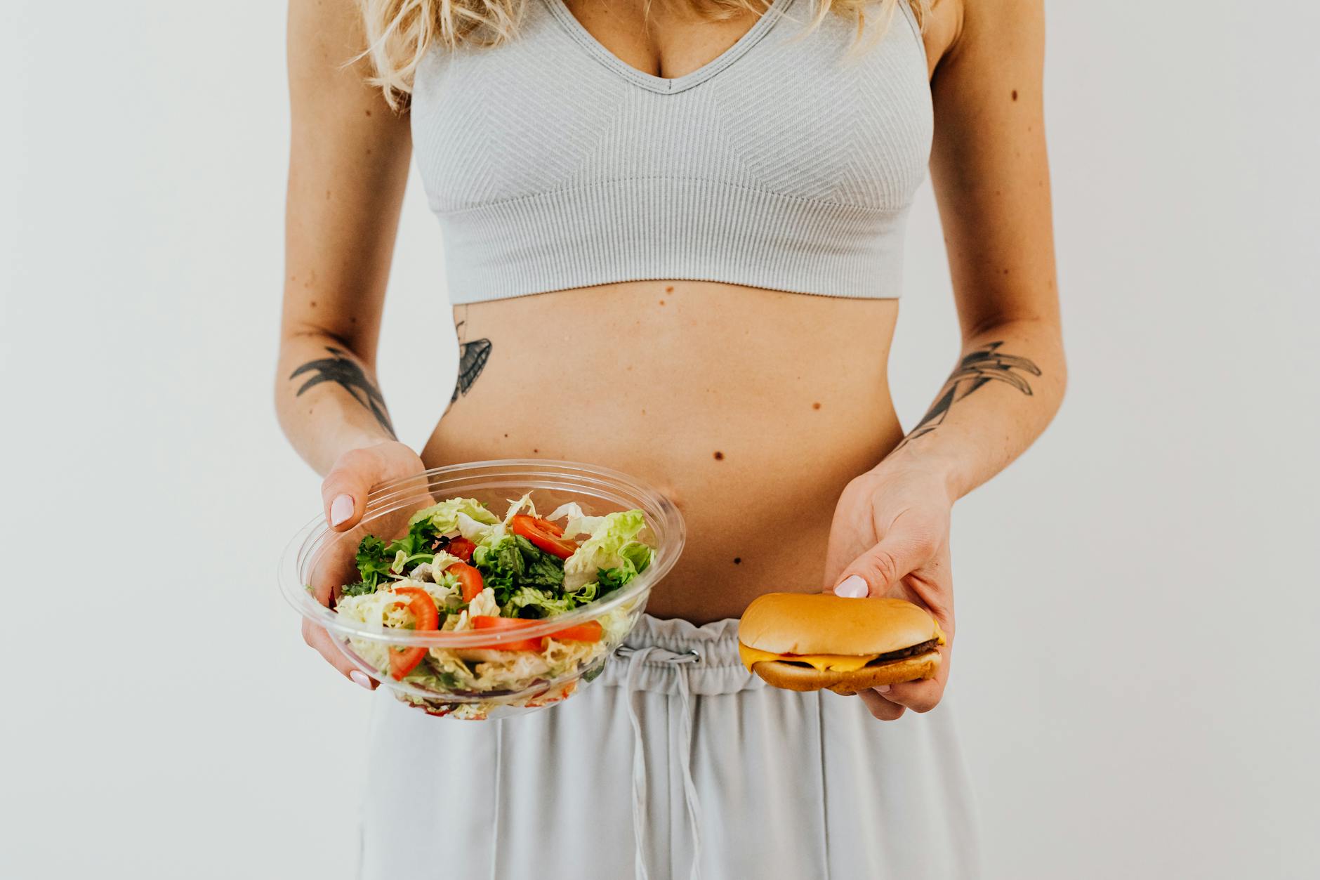 woman in white tank top holding a bowl of vegetable salad and bread